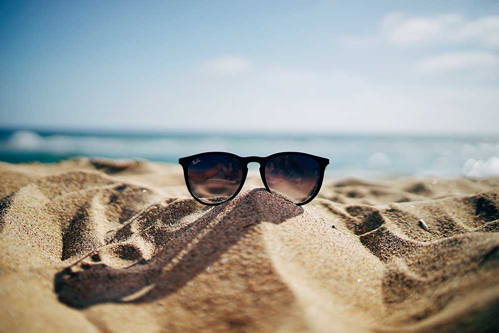 Ett par solglasögon i sanden